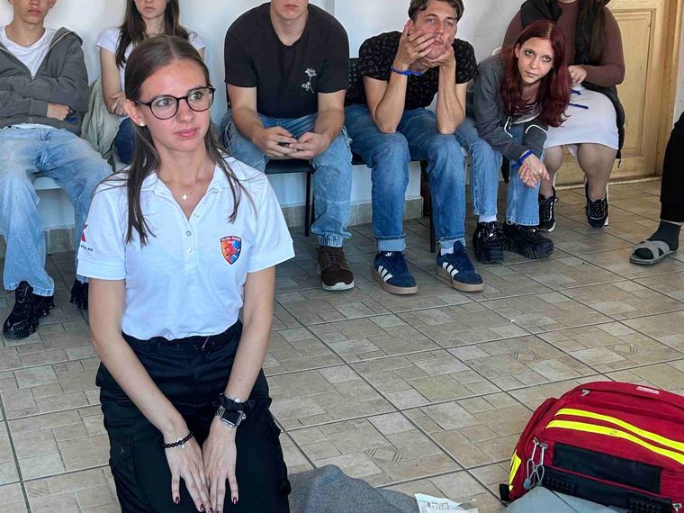 A first aid session, someone kneeling on the floor next to a medical bag while the group watches
