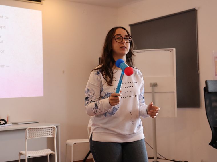 A participant speaking to the room with a soft microphone in front of a projected slide